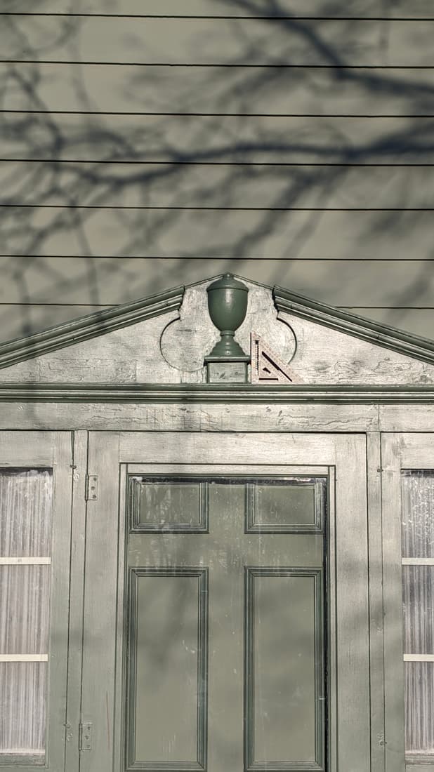 The entry pediment before work: the old finish crazed, with bare wood showing through.