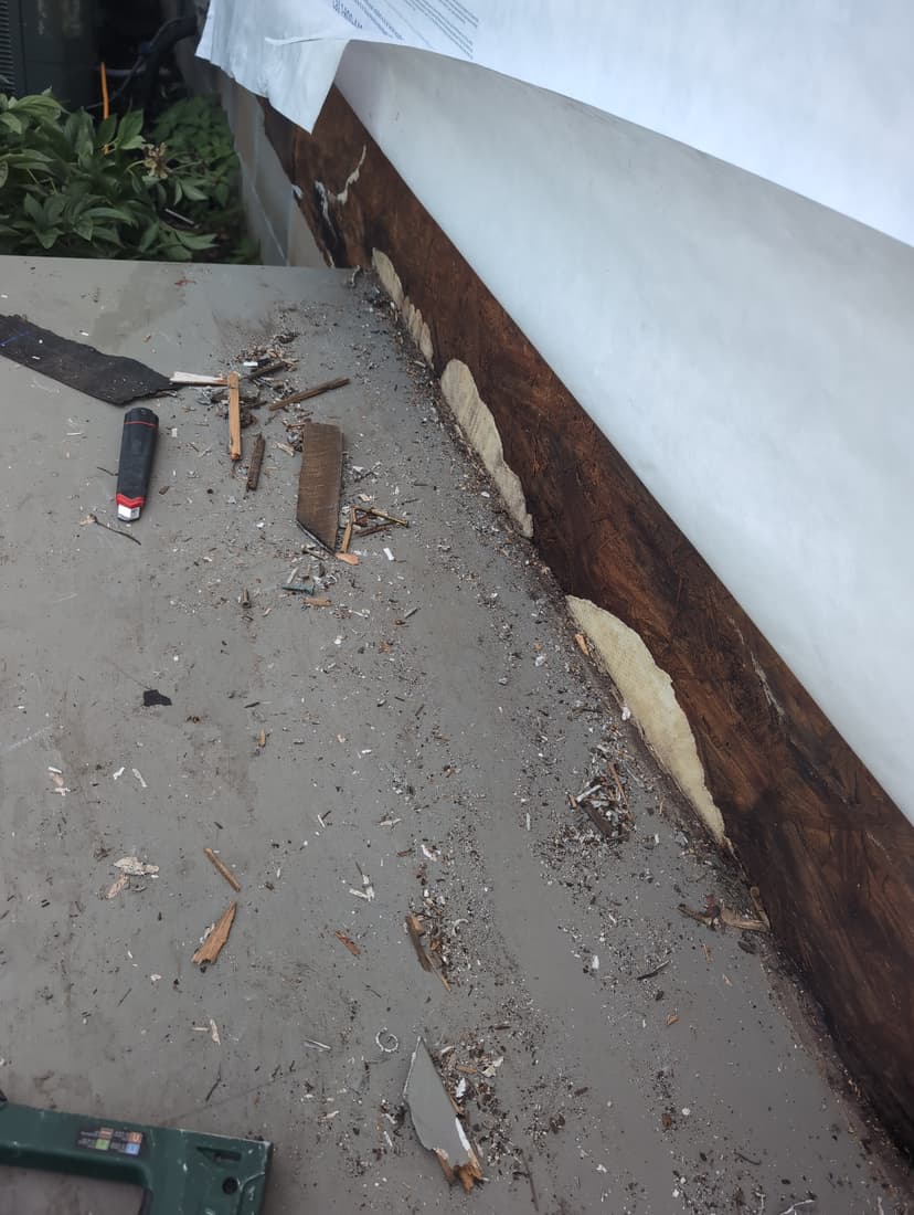 At the porch roof, the base of the wall dark and soft behind the wrap.