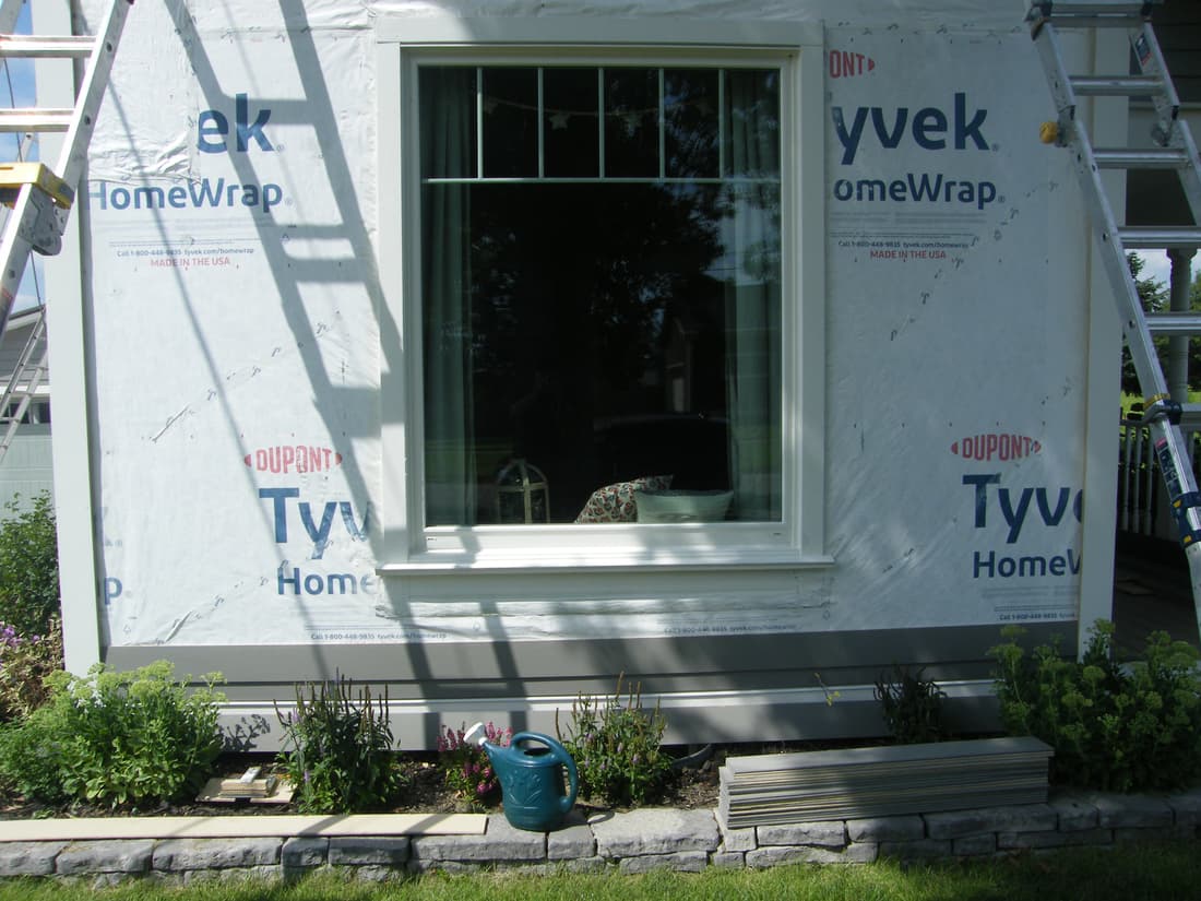 The south wall trimmed out and ready, with the siding stacked below.